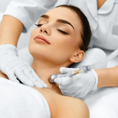 Face Skin Care. Closeup Of Beautiful Woman Getting Diamond Microdermabrasion Peeling Treatment In A Beauty Spa Salon. Cleansing Procedure. Cosmetology.
